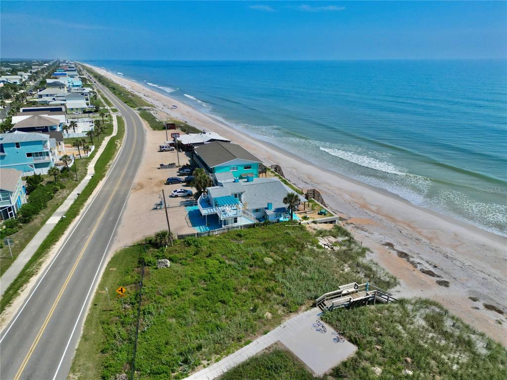 An aerial view shows a coastal road, beach houses, and a sandy shoreline along the ocean — 2815 S OCEAN SHORE BOULEVARD, FLAGLER BEACH, FL