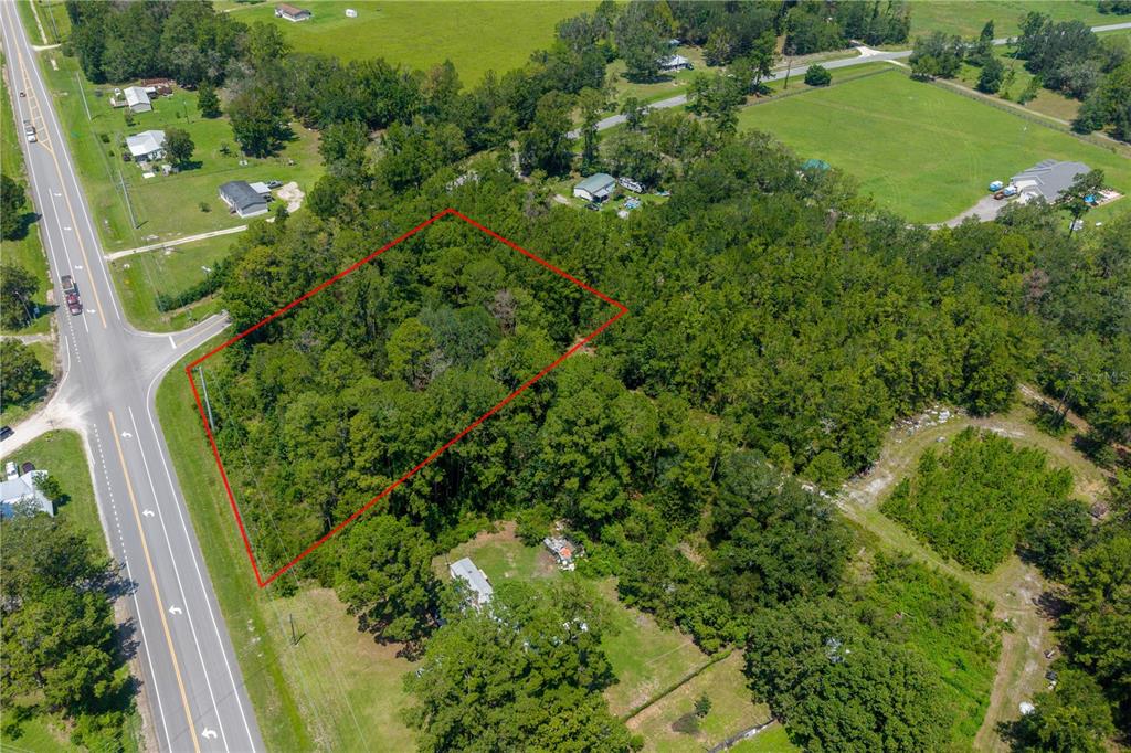 An aerial view shows a rectangular plot of land outlined in red beside a road — TBD SR 100, LAKE BUTLER, FL
