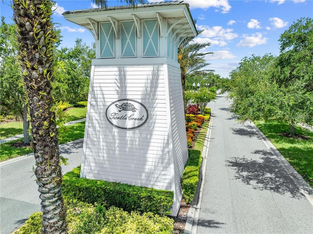 A white monument sign with a turtle logo marks the entrance to the Turtle Creek community — 1619 REFLECTION COVE, ST CLOUD, FL