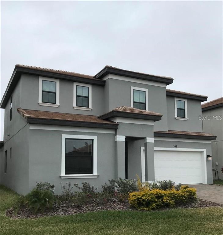 A two-story gray stucco house features a paved driveway, a white garage door, and a lawn — 209 MACAULAYS COVE, HAINES CITY, FL