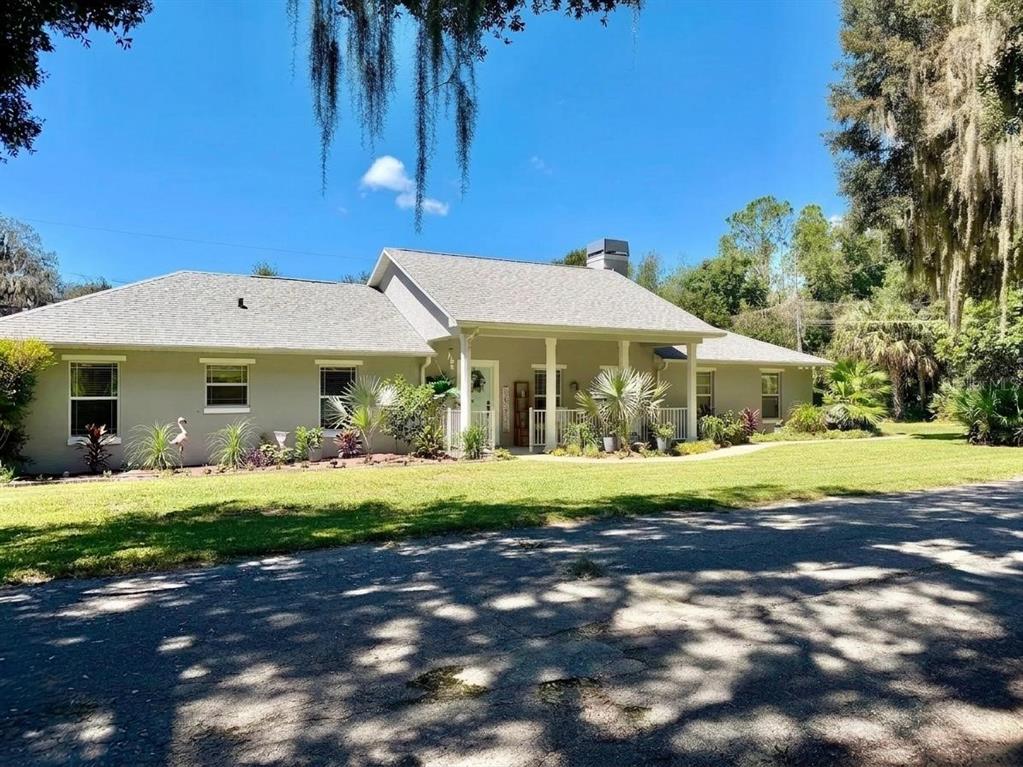 A single-story house with a gray roof and light-colored exterior sits behind a grassy lawn — 12854 SE 118TH TERRACE, OCKLAWAHA, FL