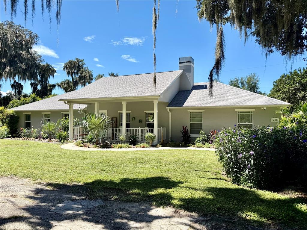 A single-story house with a covered front porch, gray siding, and a large front lawn — 12854 SE 118TH TERRACE, OCKLAWAHA, FL