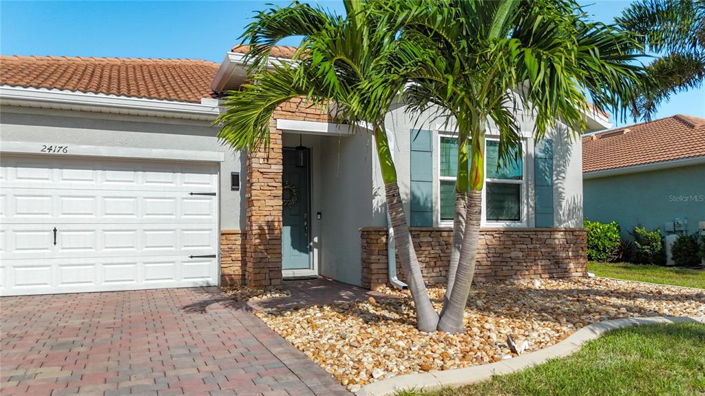 A single-story house exterior features a stone facade, a palm tree, and a paved driveway — 24176 RIVERFRONT DRIVE, PUNTA GORDA, FL