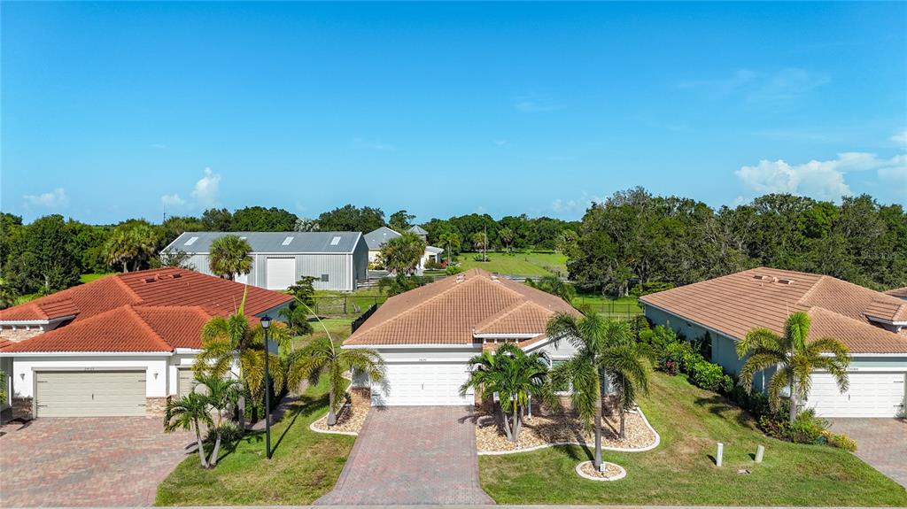 Three suburban houses with tiled roofs and paved driveways sit under a clear blue sky — 24176 RIVERFRONT DRIVE, PUNTA GORDA, FL