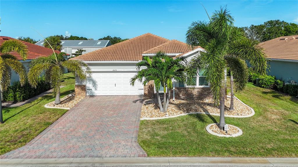 A single-story house with a tiled roof, brick driveway, and palm trees in the front yard — 24176 RIVERFRONT DRIVE, PUNTA GORDA, FL