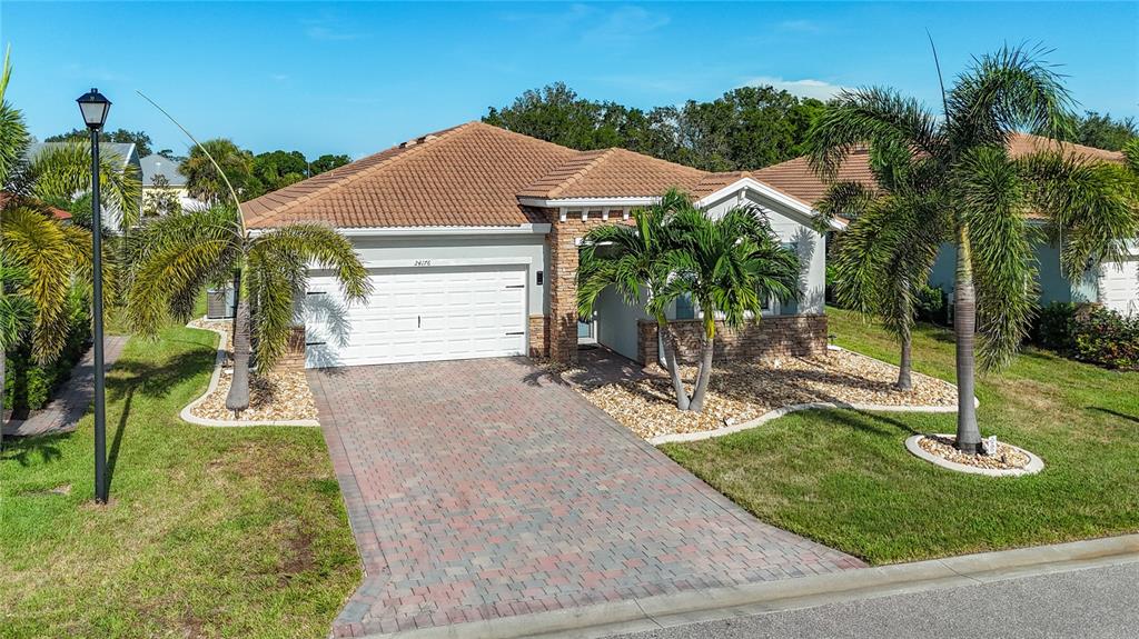 A single-story house with a tiled roof, stone accents, and a paved driveway — 24176 RIVERFRONT DRIVE, PUNTA GORDA, FL