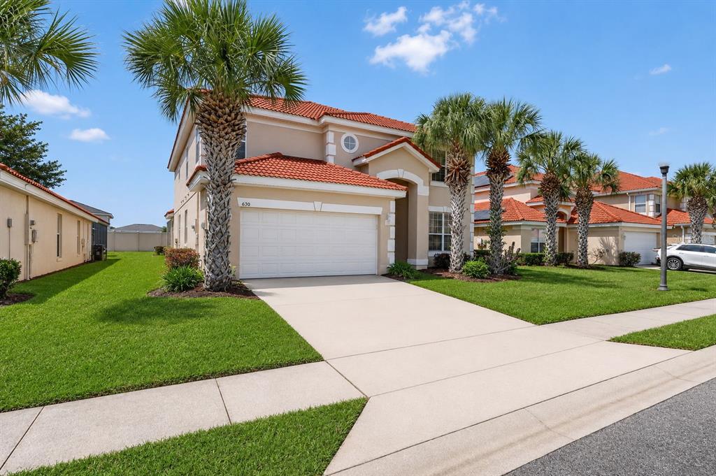 A two-story suburban house with a tan stucco exterior, red tile roof, and palm trees — 630 SOLANA CIRCLE, DAVENPORT, FL