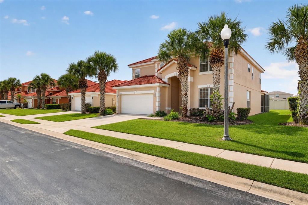 A two-story suburban house with a tile roof, palm trees, and a concrete driveway — 630 SOLANA CIRCLE, DAVENPORT, FL