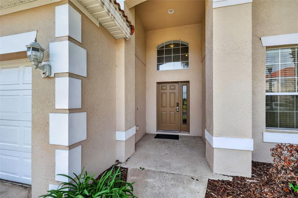 The exterior entrance features a tan stucco facade, a brown front door, and a window — 630 SOLANA CIRCLE, DAVENPORT, FL