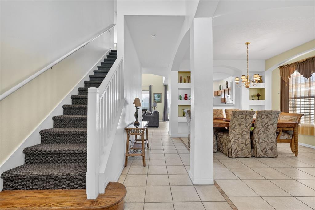 A staircase with dark carpet leads up beside a dining area with tiled floors — 630 SOLANA CIRCLE, DAVENPORT, FL