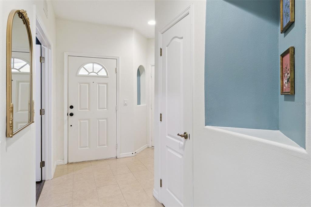 A white front door opens into a tiled entryway with a mirror and blue alcove — 907 OCASO LANE UNIT 101, ROCKLEDGE, FL