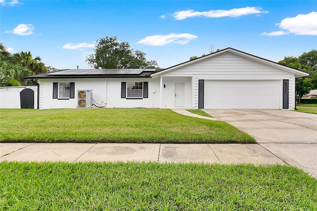 A single-story white house with a two-car garage, solar panels, and a front lawn — 2494 CASTLEWOOD ROAD, MAITLAND, FL