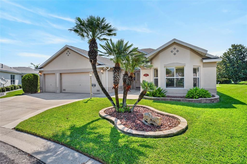 A single-story house with a beige exterior, a three-car garage, and a landscaped front yard — 3182 KEARNS CORNER, THE VILLAGES, FL