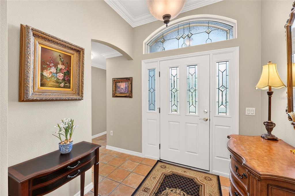 A tiled entryway features a white front door with glass panels and a decorative transom window — 3182 KEARNS CORNER, THE VILLAGES, FL