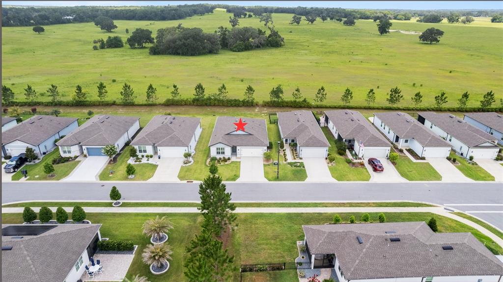 An aerial view shows a row of suburban houses bordering a large, open green field — 9407 SW 52ND LOOP, OCALA, FL
