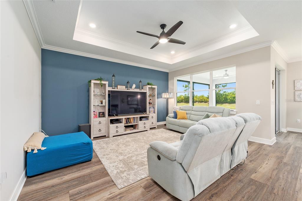 A living room features a blue accent wall, tray ceiling, light flooring, and neutral furniture — 9407 SW 52ND LOOP, OCALA, FL