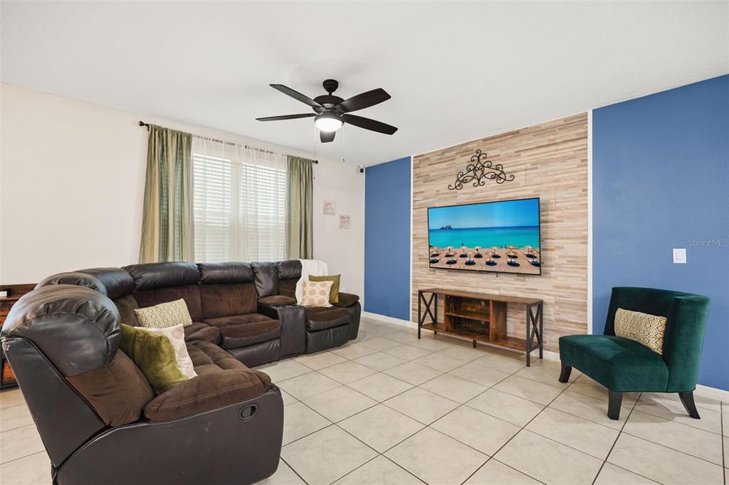 A living room features a brown sectional sofa, a wall-mounted television, and a green chair — 428 MCKENNA DRIVE, WINTER HAVEN, FL
