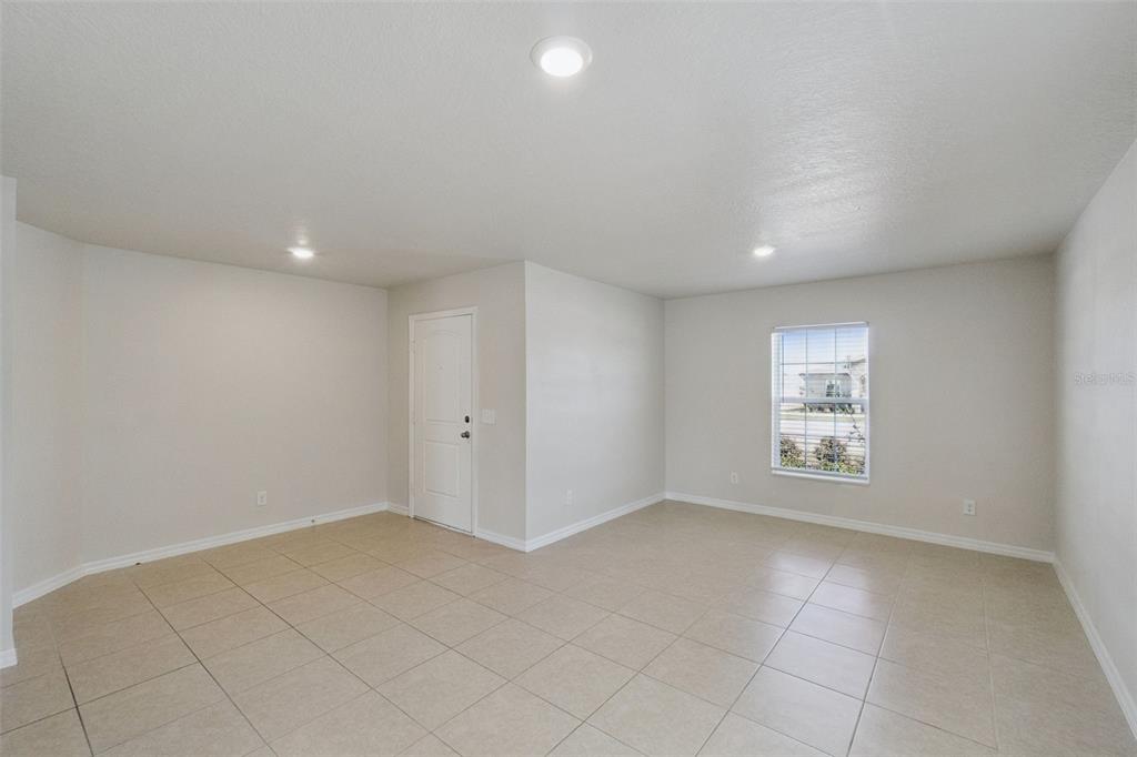 An empty room features light-colored tile flooring, neutral walls, recessed lighting, and a single window — 1729 CANAAN LOOP, DUNDEE, FL