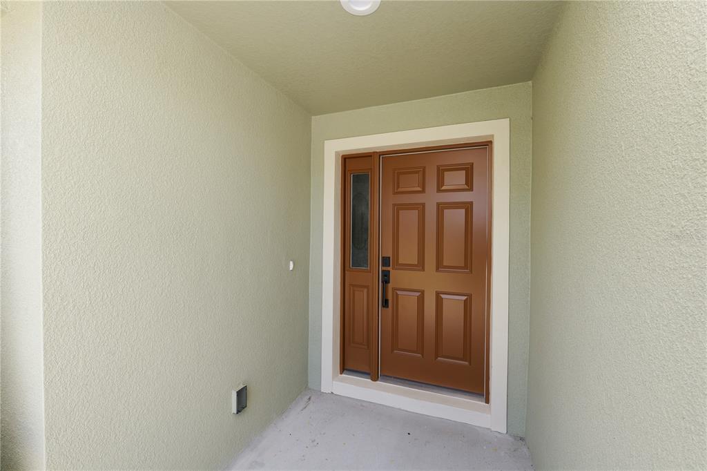 A brown front door with a side window is set within a light-colored stucco entryway — 23 8TH ST S, EAGLE LAKE, FL
