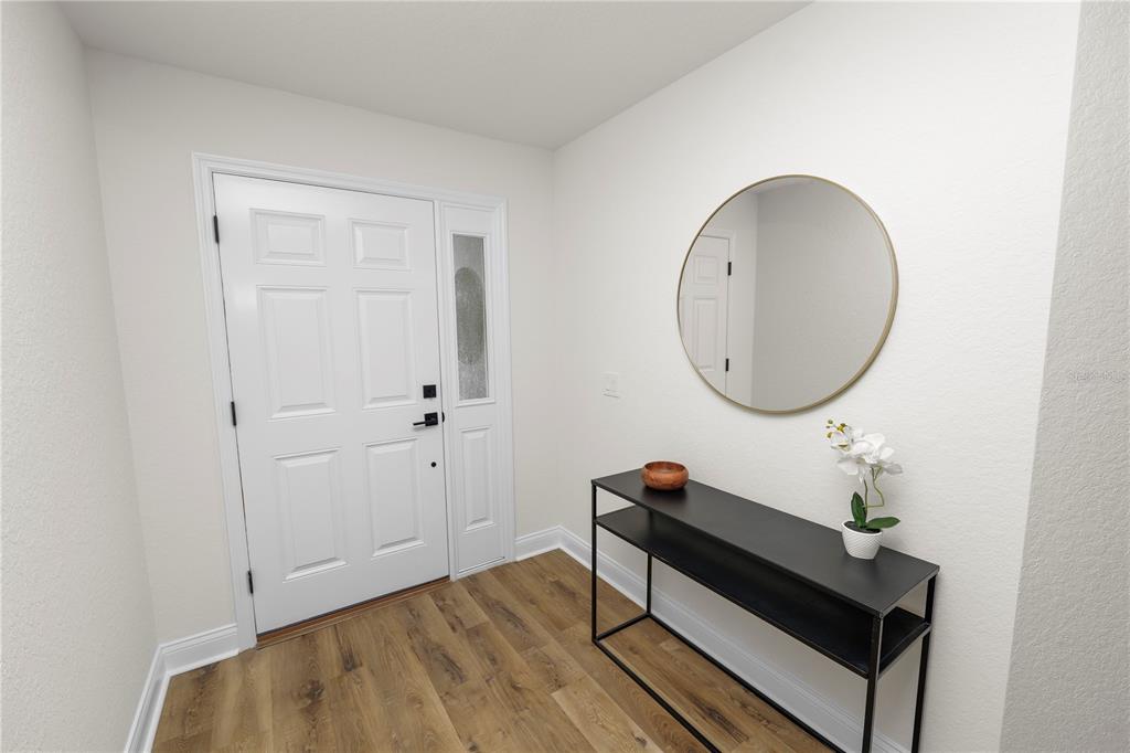 A bright entryway features wood-look flooring, a white front door, a console table, and a mirror — 23 8TH ST S, EAGLE LAKE, FL