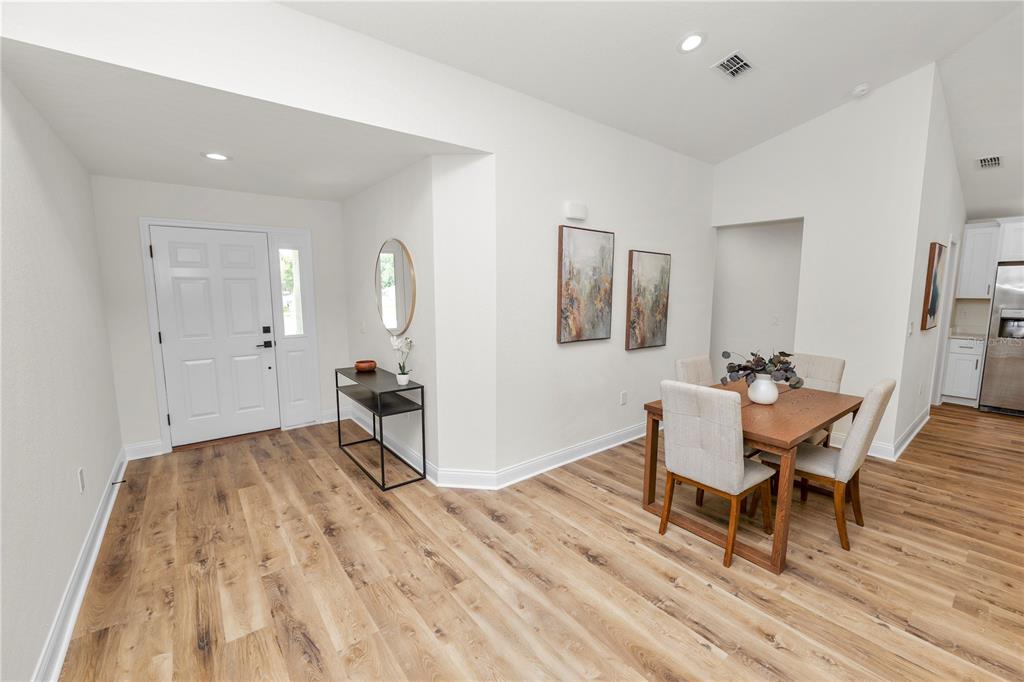An entryway with wood-look flooring leads into a dining area with a table and chairs — 23 8TH ST S, EAGLE LAKE, FL