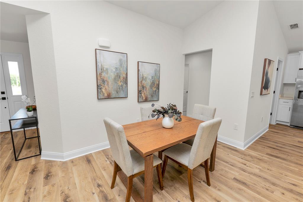 A dining area features a wooden table, four upholstered chairs, and two abstract wall paintings — 23 8TH ST S, EAGLE LAKE, FL