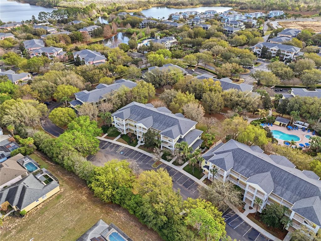 An aerial view shows multiple multi-story apartment buildings surrounded by trees, parking lots, and pools — 410 LUCAYA LOOP UNIT 4204, DAVENPORT, FL