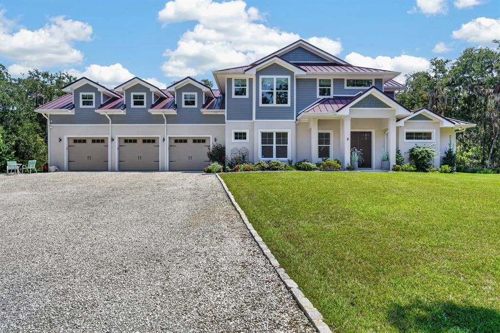 A two-story house with a three-car garage, metal roof, and a gravel driveway — 8 LEXINGTON COURT, FLAGLER BEACH, FL