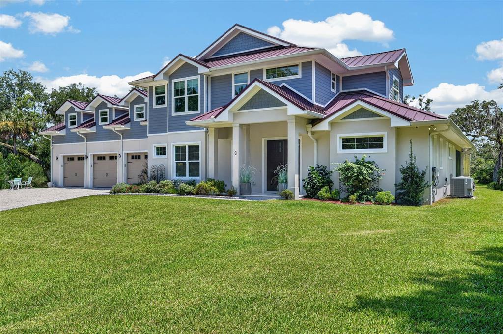 A two-story house with blue siding, a metal roof, and a three-car garage — 8 LEXINGTON COURT, FLAGLER BEACH, FL