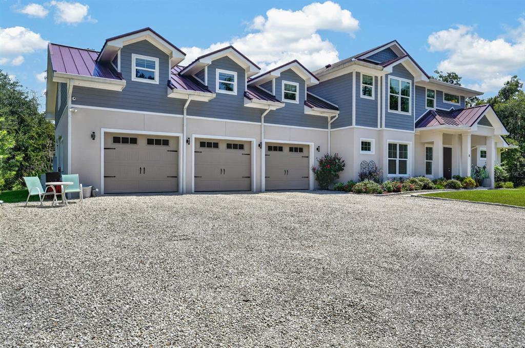 A two-story house with a three-car garage, metal roof, and a gravel driveway — 8 LEXINGTON COURT, FLAGLER BEACH, FL