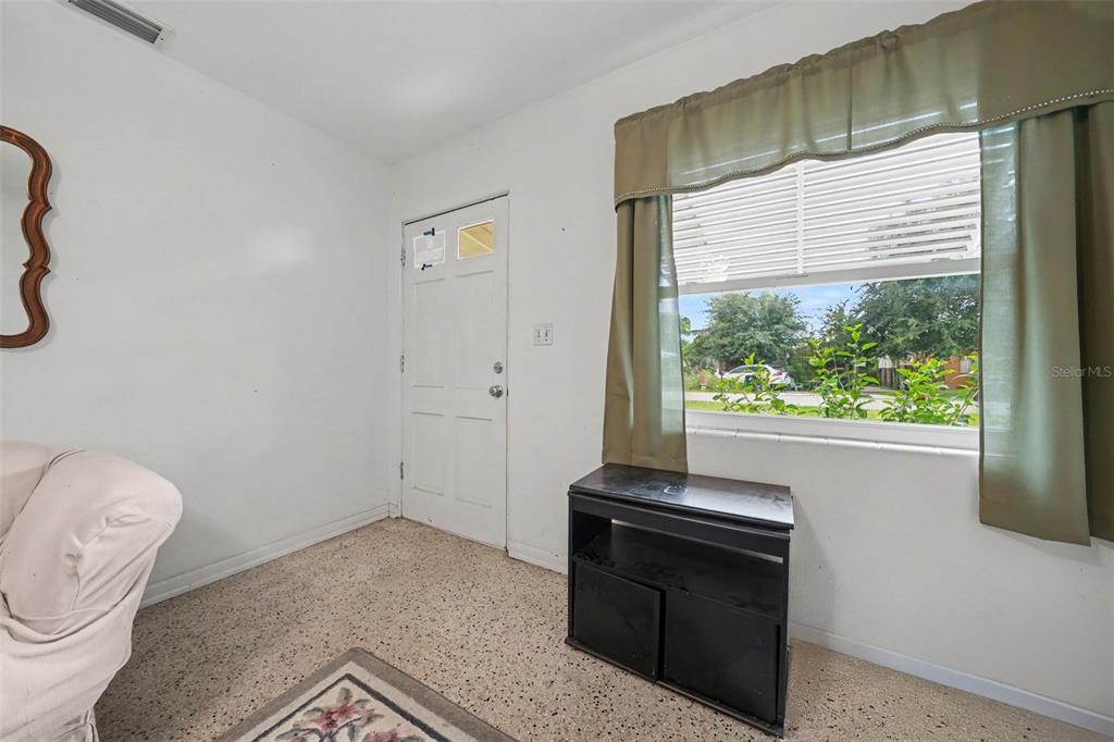 A room with white walls, a white door, a window with curtains, and speckled flooring — 1941 OGLESBY AVENUE, WINTER PARK, FL