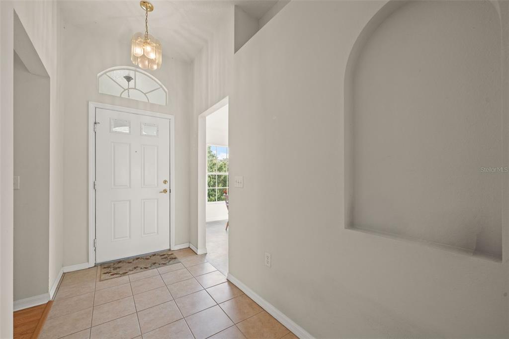 An entryway features a white front door, tiled flooring, a light fixture, and an arched niche — 18208 BRELAND DRIVE, HUDSON, FL