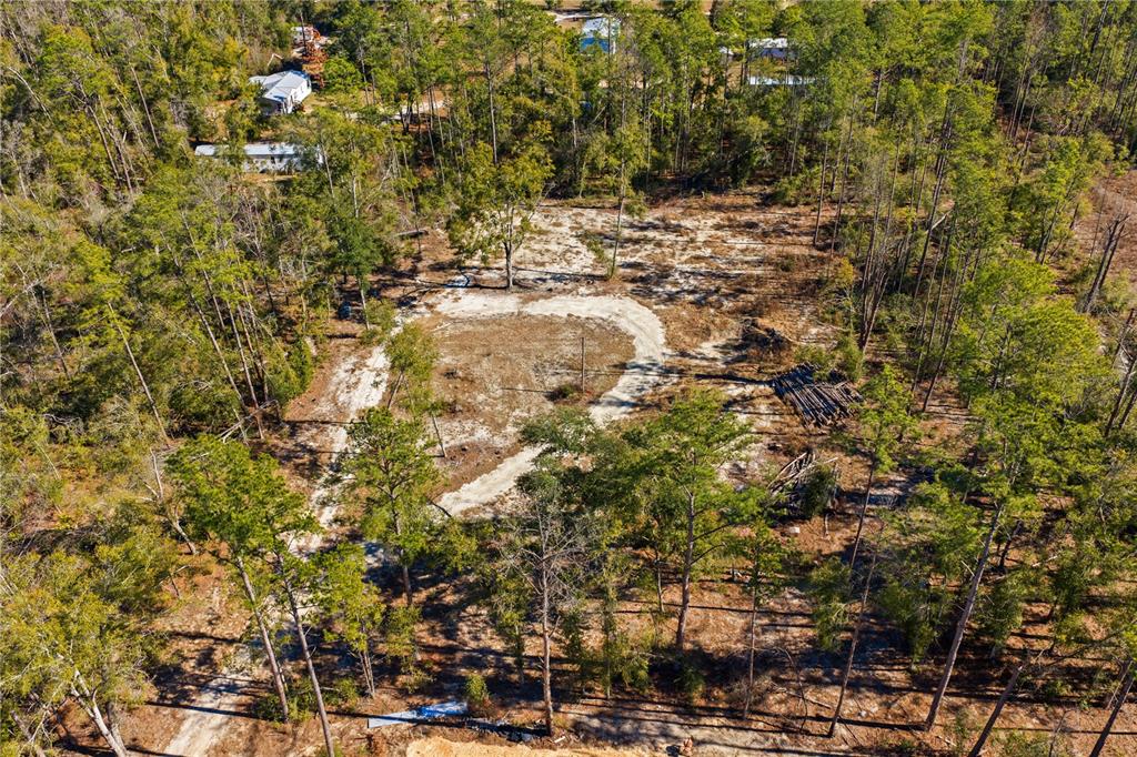 An aerial view shows a cleared, sandy lot surrounded by dense pine trees — 12TH TERRACE, LIVE OAK, FL