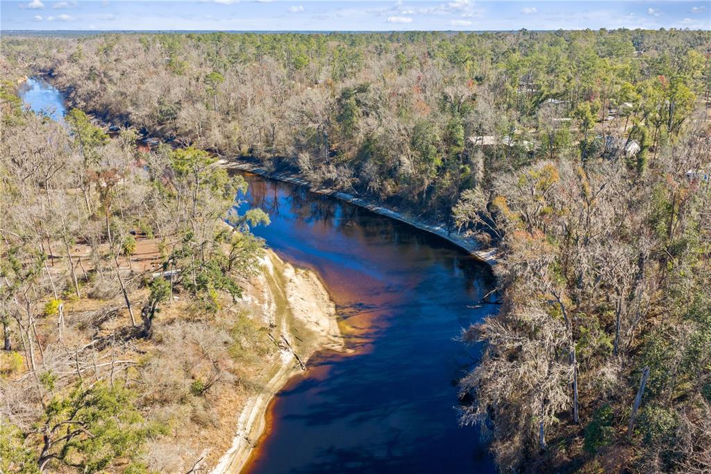 An aerial view of a dark, winding river flowing through a wooded landscape — 12TH TERRACE, LIVE OAK, FL