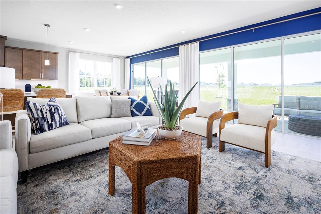 A living room features a beige sofa, two wooden armchairs, and a hexagonal wicker table — 22177 PINE GROVE LOOP, LEESBURG, FL