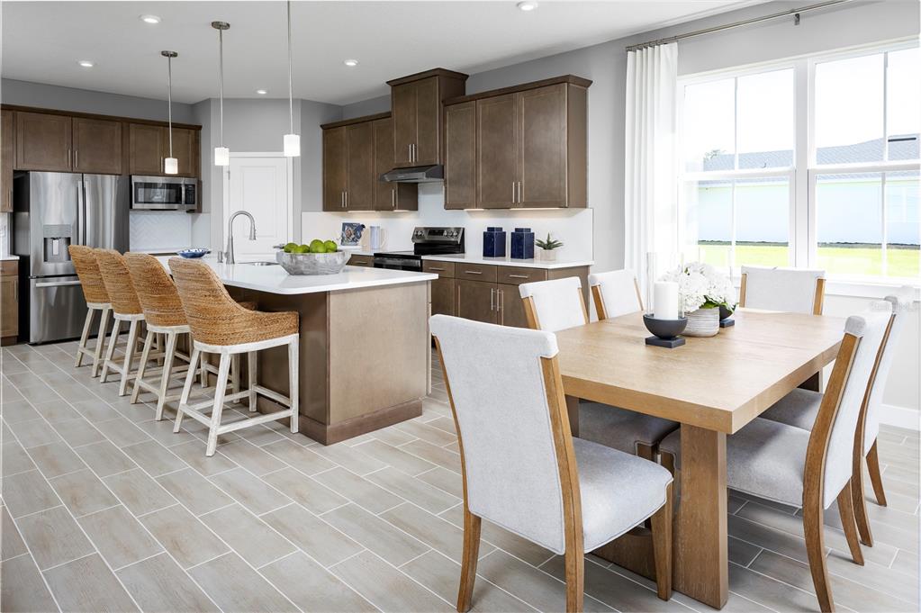 A kitchen with brown cabinets and a dining area with a wooden table and chairs — 22177 PINE GROVE LOOP, LEESBURG, FL
