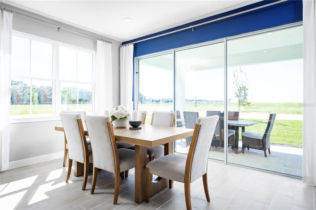 A dining room features a wooden table, upholstered chairs, and sliding glass doors to a patio — 22177 PINE GROVE LOOP, LEESBURG, FL