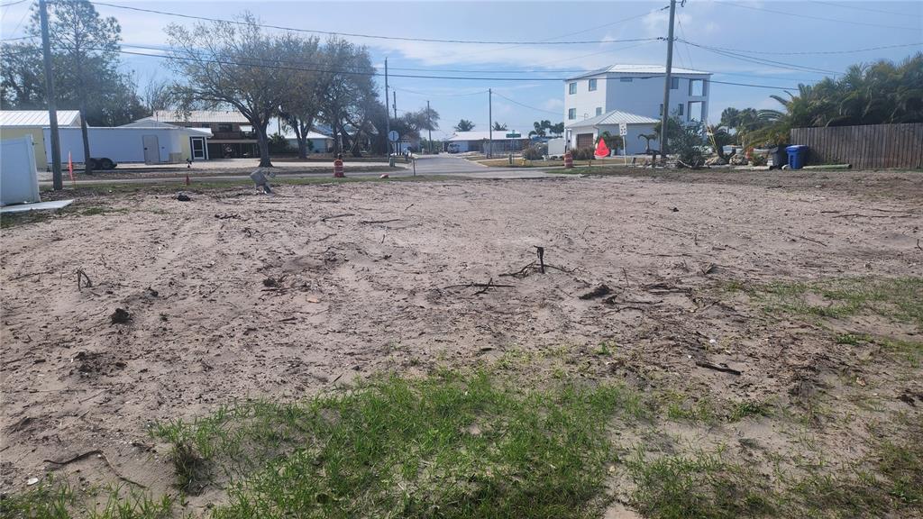 A vacant, sandy residential lot with sparse vegetation and surrounding houses in the background — 3203 W SHELL POINT ROAD, RUSKIN, FL