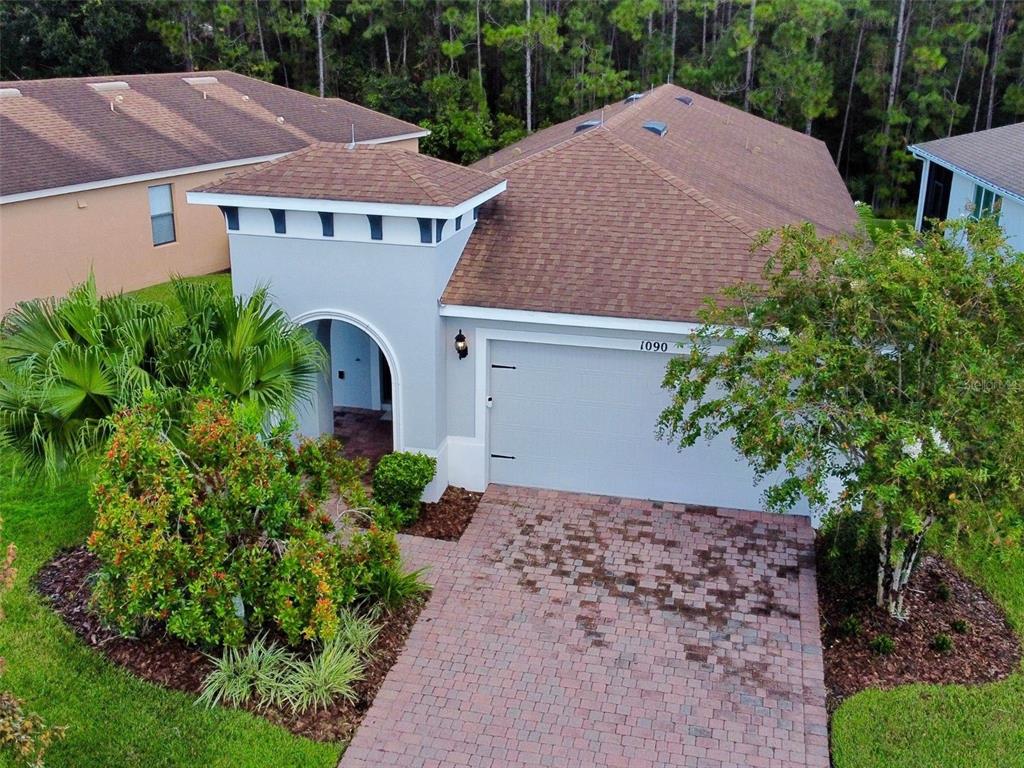 An aerial view shows a single-story house with a paved driveway and a tiled roof — 1090 HARBOR RIDGE DRIVE, POINCIANA, FL