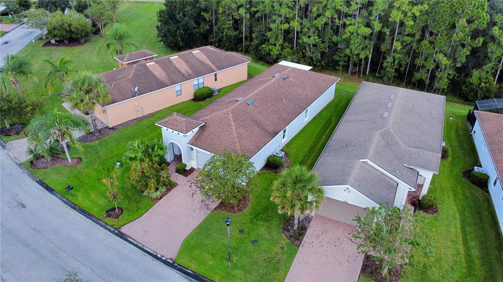 An aerial view shows three suburban houses with brown roofs and paved driveways surrounded by lawns — 1090 HARBOR RIDGE DRIVE, POINCIANA, FL