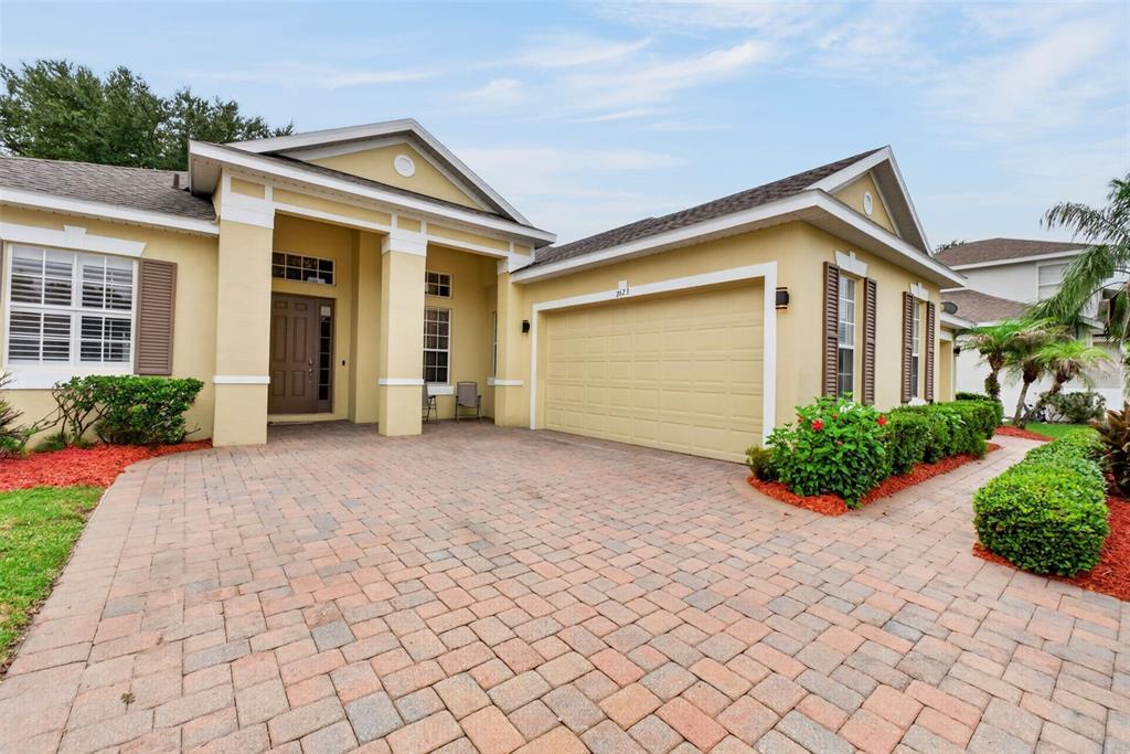 A single-story house with a beige stucco exterior, a two-car garage, and a paver driveway — 2623 PALASTRO WAY, OCOEE, FL