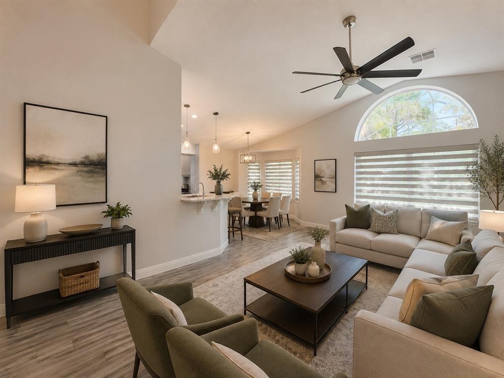 A living room with a vaulted ceiling, ceiling fan, sectional sofa, and an adjacent dining area — 2791 PICADILLY CIRCLE, KISSIMMEE, FL
