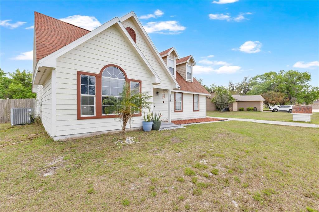A two-story house with cream siding, a large arched window, and a brown shingled roof — 5054 ARRAPAHOE STREET, ST CLOUD, FL