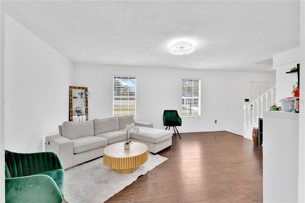 A living room features a light-colored sectional sofa, a round wooden coffee table, and flooring — 5054 ARRAPAHOE STREET, ST CLOUD, FL