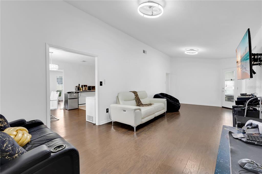 A living room with white walls, dark wood floors, and a white sofa — 5054 ARRAPAHOE STREET, ST CLOUD, FL