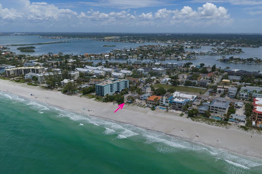 A swimming pool with a waterfall and hot tub overlooks the ocean at sunset — 2308 BEACH TRAIL, INDIAN ROCKS BEACH, FL