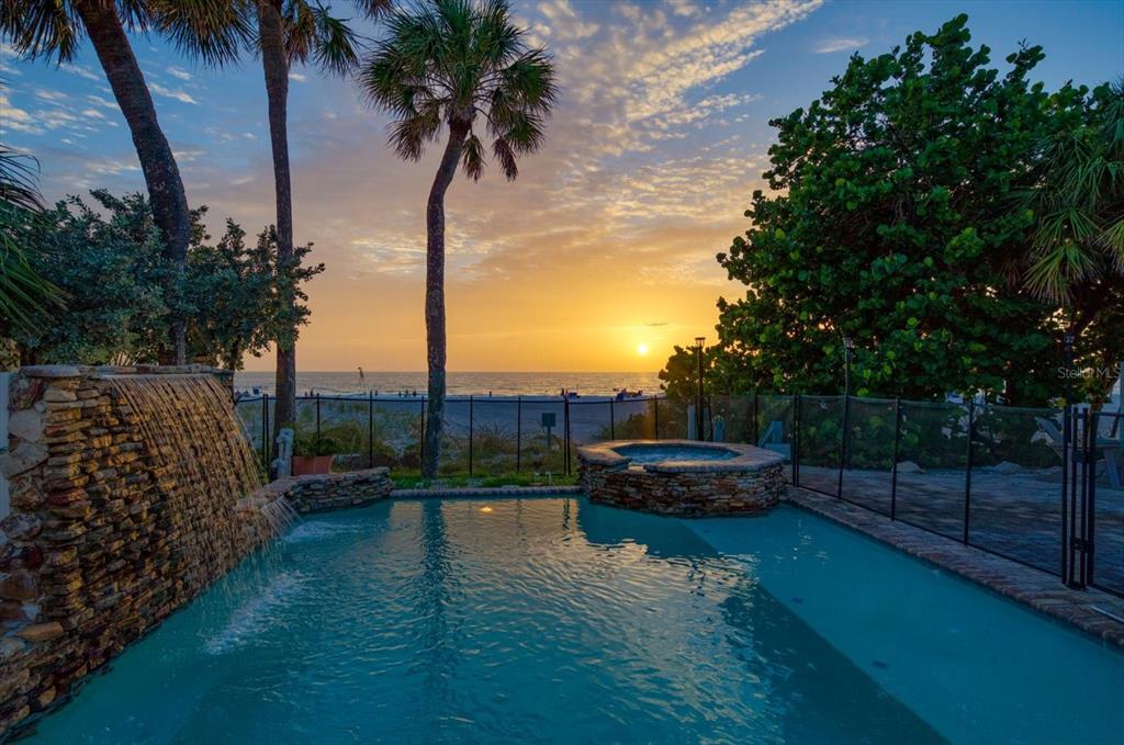 A paved patio area features two wicker chairs, wall-mounted fish decor, and blue double doors — 2308 BEACH TRAIL, INDIAN ROCKS BEACH, FL