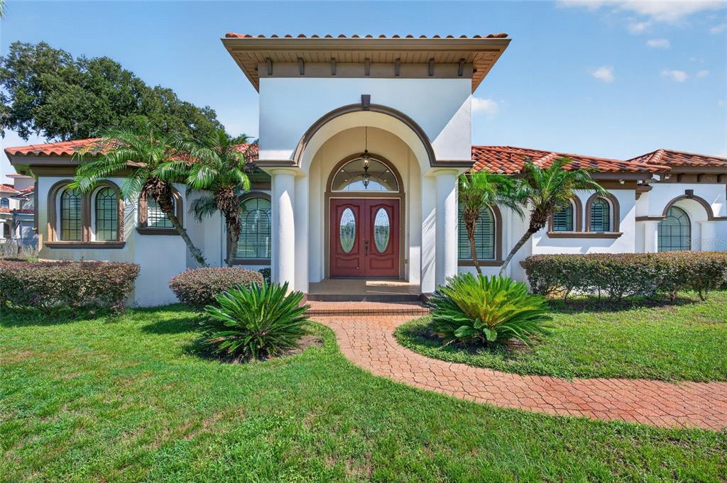 A single-story house with a red tile roof, arched windows, and a brick walkway entrance — 301 PRUETT ROAD, SEFFNER, FL