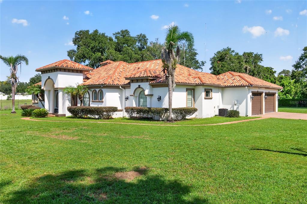 A single-story stucco house with a terracotta tile roof and an attached two-car garage — 301 PRUETT ROAD, SEFFNER, FL