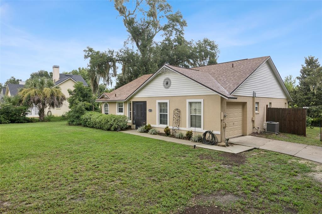 A single-story house with a tan stucco exterior, a brown shingled roof, and a garage — 30724 FAIRVIEW AVENUE, TAVARES, FL